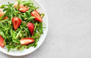 Fresh Strawberry Arugula Salad With Pine Nuts Served on a Bright Day photo