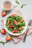 Fresh Strawberry Arugula Salad With Pine Nuts Served on a Bright Day photo