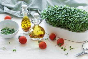 Tray of radish microgreens. Olive oil and tomatoes on the table. photo