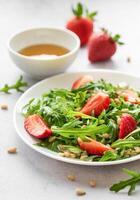 Fresh Strawberry Arugula Salad With Pine Nuts Served on a Bright Day photo