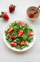 Fresh Strawberry Arugula Salad With Pine Nuts Served on a Bright Day photo