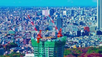 A timelapse of moving cranes at top of the building in Tokyo high angle long shot zoom video