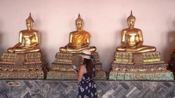 Tourists look at golden Buddha video