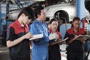 especialista conferencia. masculino supervisor ingeniero describir automotor suspensión fijación con mecánico trabajador personal equipos para reparar trabajo a coche Servicio garaje y mantenimiento trabajos en automóvil industria. foto