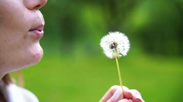 A woman is holding a dandelion in her hand. She is looking at it with a sad expression on her face. video