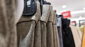 Rows of trousers in a clothing store hanging neatly on hangers. photo