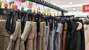 Rows of trousers in a clothing store hanging neatly on hangers. photo