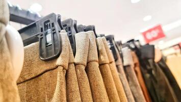 Rows of trousers in a clothing store hanging neatly on hangers. photo