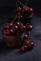 Organic juicy cherry in a bowl on dark background. Close-up photo, low key photo