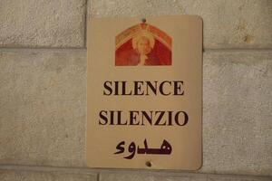 firmar de silencio en el Iglesia en un Roca pared. inscripción en Tres idiomas selectivo atención foto