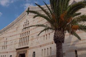 Palm with dates, blue sky and Basilica of the Annunciation in Nazareth. Light clouds, sunny day photo