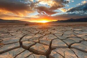 Sunset over Cracked Desert Soil and Mountain Range photo