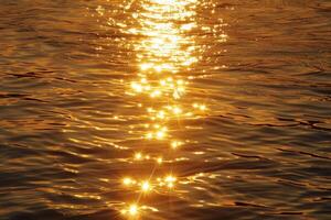 dorado destellos en mar agua a puesta de sol foto