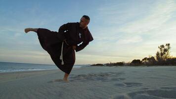 Monk athlete from a karate kick in the beach photo