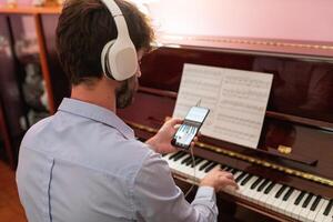 hombre haciendo remoto música piano lección con teléfono inteligente cámara foto