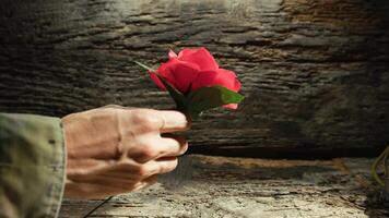 Hand of a soldier holding a rose near a flag and boots on memorial day photo