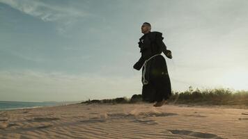 religioso monje lo hace saltar cuerda en el suave arena playa foto