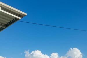 View of the edge of the metal roof with cable hanging on residential roof top. Clear blue sky. photo