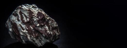 Piemontite is a rare precious natural stone on a black background. . Header banner mockup with space. photo