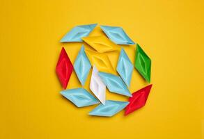 A group of colorful paper boats clustered on a yellow background photo