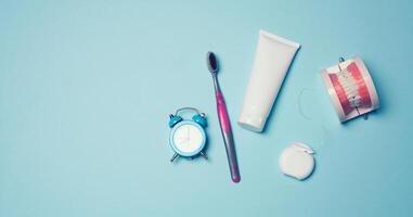 Model of a human jaw with white teeth, dental floss and toothpaste on a blue background photo