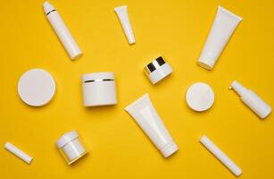 Various types of white plastic packaging, bottle, jar, tube on a yellow background. Container for cosmetics photo