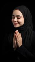 European woman wearing scarf is praying and smiling on black background photo