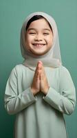 Southeast asian woman wearing scarf is praying and smiling on green background photo