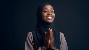 africano mujer vistiendo bufanda es Orando y sonriente en negro antecedentes foto