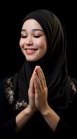 Southeast asian woman wearing scarf is praying and smiling on black background photo