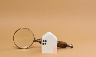 Wooden house and a magnifying glass, representing the concept of real estate purchase photo