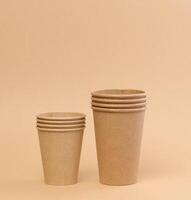 Stack of brown paper disposable cardboard cups on beige background photo