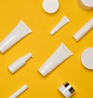 Various types of white plastic packaging, bottle, jar, tube on a yellow background. photo