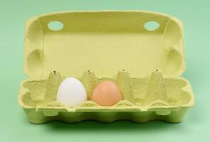 Two chicken eggs in a paper box on a green background photo