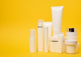 Various types of white plastic packaging, bottle, jar, tube on a yellow background. Container for cosmetics photo