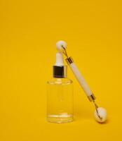 White transparent glass bottle with pipette and roller massager photo