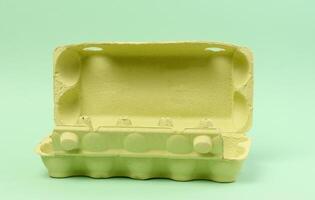 Open green recycled egg carton box on green background, storage photo