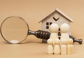 Magnifying glass and a family of wooden figures on the background of a house, the concept of searching for real estate rental photo