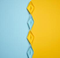 Paper boats on a yellow background, top view, representing the concept of unity and achieving common goals. photo