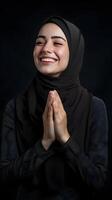 European woman wearing scarf is praying and smiling on black background photo