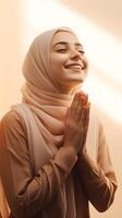 European woman wearing scarf is praying and smiling on brown background photo