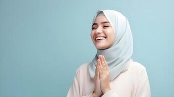 European woman wearing scarf is praying and smiling on blue background photo