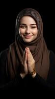 European woman wearing scarf is praying and smiling on black background photo