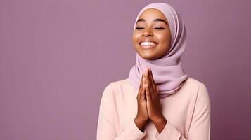 African woman wearing scarf is praying and smiling on purple background photo