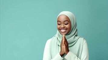 African woman wearing scarf is praying and smiling on green background photo