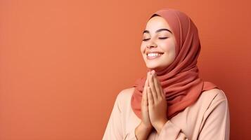 European woman wearing scarf is praying and smiling on red background photo