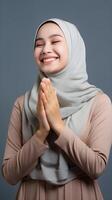 Southeast asian woman wearing scarf is praying and smiling on white background photo