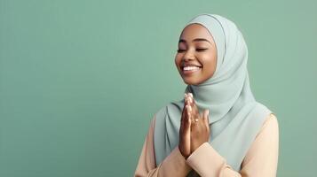 African woman wearing scarf is praying and smiling on green background photo