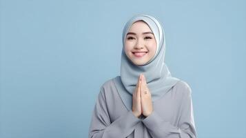 Southeast asian woman wearing scarf is praying and smiling on blue background photo