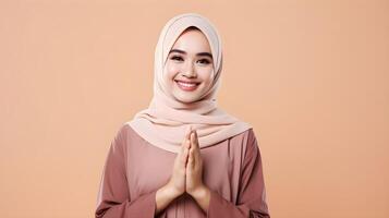 Southeast asian woman wearing scarf is praying and smiling on brown background photo